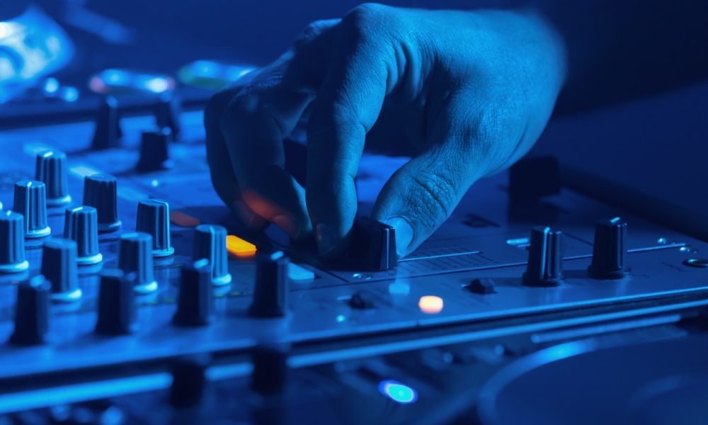 Person indstiller sin dj pult med blåt lys